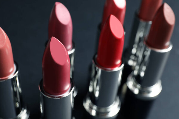 Set of different lipsticks on grey background, closeup. Cosmetic product