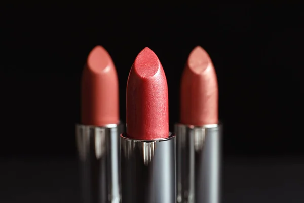 Different lipsticks on dark background. Cosmetic product