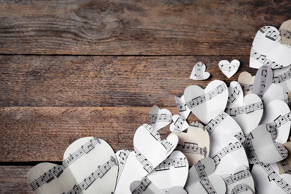 Paper hearts with music notes and space for text on wooden background, flat lay