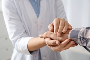 Kadın doktor adam açık renkli, closeup eller üzerinde rahatlatıcı. Yardım ve destek kavramı