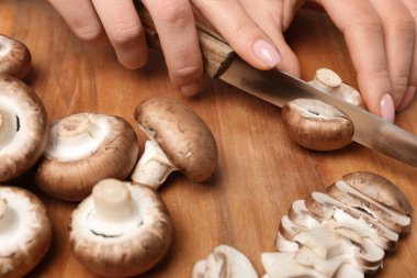 Genç kadın kesme taze champignon ahşap masa, closeup görünümü mantar