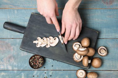 Genç kadın kesme taze champignon ahşap masa, üstten görünüm mantar