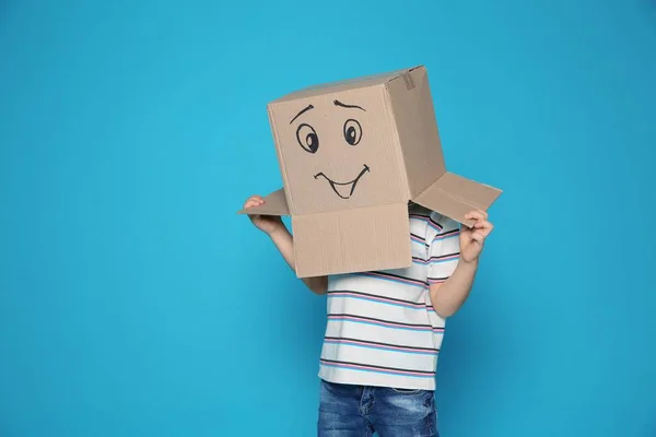 Criança Bonito Vestindo Caixa Papelão Com Rosto Sorridente Fundo Cor — Fotografia de Stock