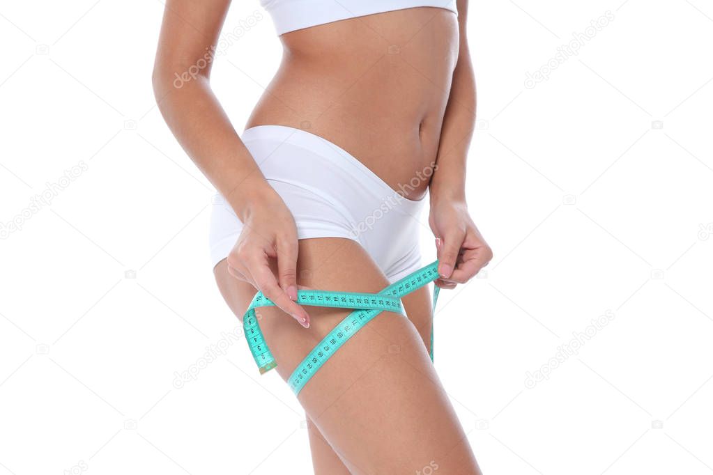 Slim woman measuring her thigh on white background, closeup. Weight loss