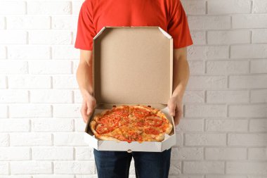 Açılan pizza kutusu beyaz duvara yakın olan genç adam. Gıda dağıtım hizmeti