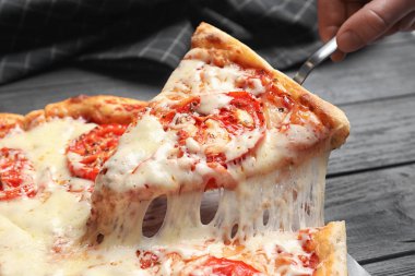 Kadın alarak dilim sıcak peynir pizza Margherita masada, portre