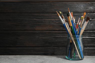 Boya fırçaları ahşap arka plan karşı masada ile jar. Metin için yer