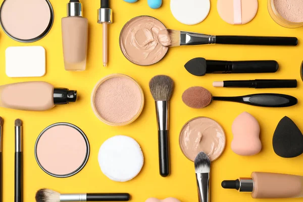 Flat lay composition with skin foundation, powder and beauty accessories on color background