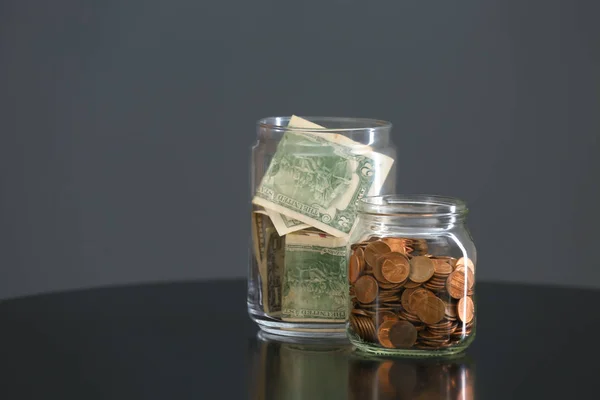 Donation jars with money on table against grey background