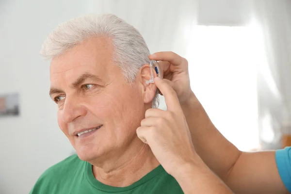 Joven Poniendo Audífono Oído Del Padre Interior —  Fotos de Stock