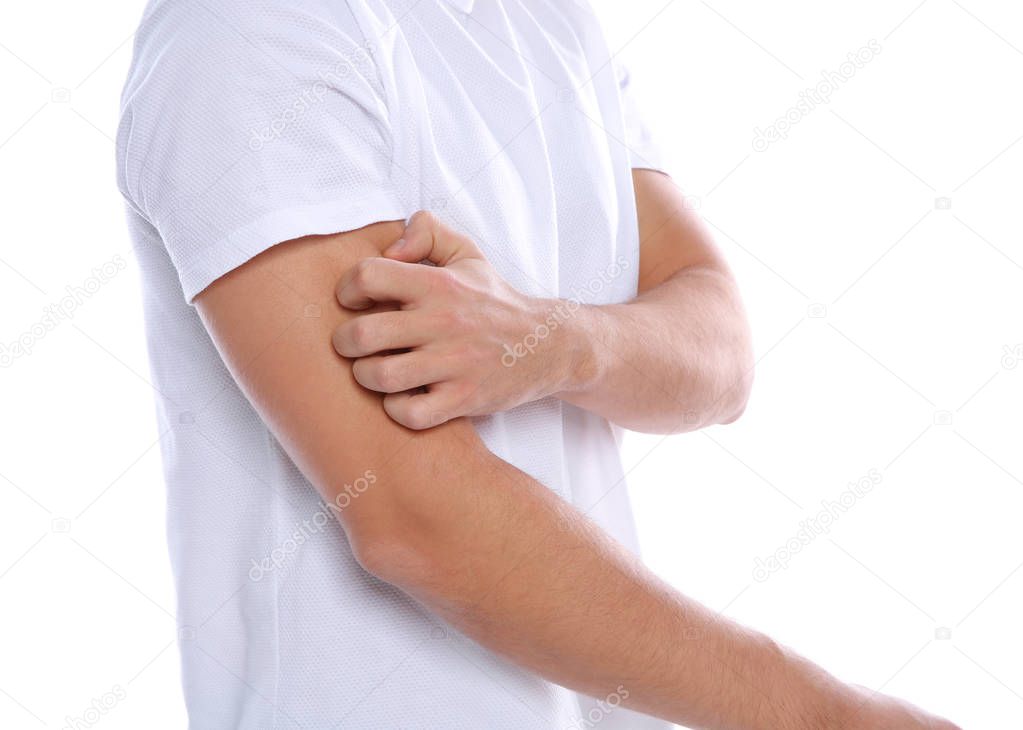 Young man scratching arm on white background, closeup. Annoying itch