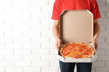 Açılan pizza kutusu beyaz tuğla duvar, metin için yer yakın olan genç adam. Gıda dağıtım hizmeti.