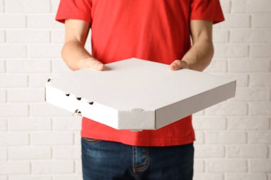 Pizza kutusu beyaz duvara yakın olan genç adam. Gıda dağıtım hizmeti