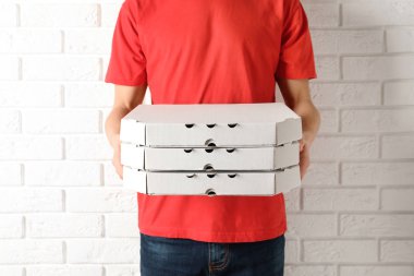 Pizza kutuları beyaz duvara yakın olan genç adam. Gıda dağıtım hizmeti