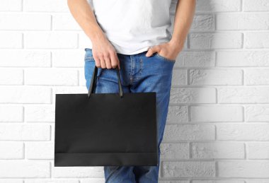Kağıt alışveriş çantası mock-up duvara tutan adam