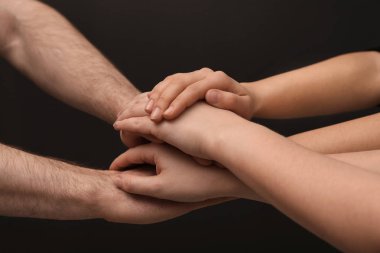 Genç insanlar ellerini birlikte koyu arka plan üzerinde closeup koyarak