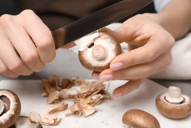 Genç kadın soyma taze champignon masada, closeup mantar