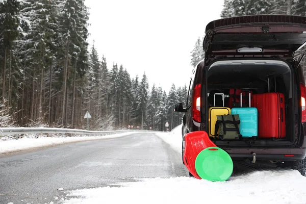 Car with open trunk full of luggage near road, space for text. Winter vacation