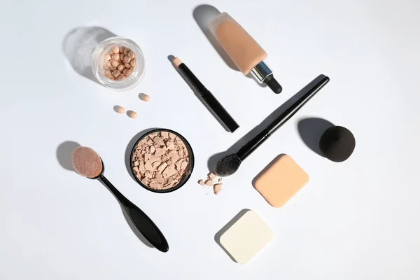 Flat lay composition with skin foundation and powder on white background