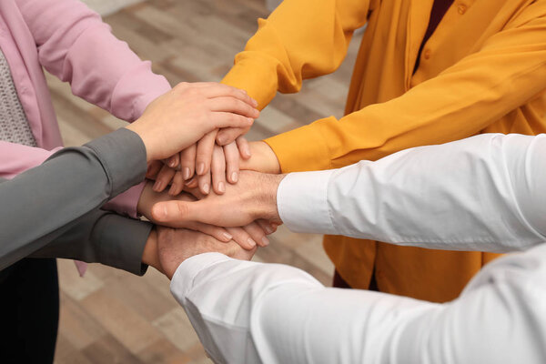 Young people putting their hands together indoors, closeup