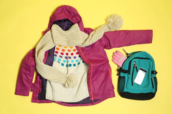 Flat lay composition with warm clothes for winter vacation on color background