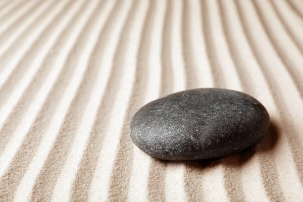 Zen garden stone on sand with pattern, space for text. Meditation and harmony
