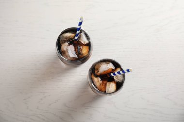 Buz küpleri ve payet Beyaz ahşap arka planda, üstten görünüm cola serinletici gözlük