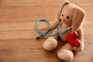 Oyuncak tavşan, stetoskop, kalp ve ahşap arka plan üzerinde metin için yer. Çocuk doktoru