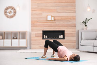 Evde egzersiz yaparak fitness giysili genç kadın