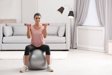 Genç kadın fitness Ball evde dumbbells ile egzersiz yaparak. Metin için yer