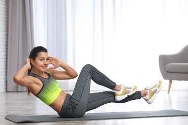 Evde egzersiz yaparak fitness giysili genç kadın. Metin için yer