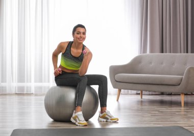 Genç kadın fitness Ball evde dumbbells ile egzersiz yaparak. Metin için yer
