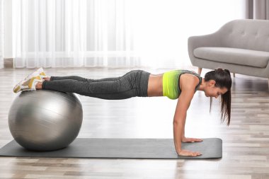 Genç kadın fitness topu evde ile egzersiz yaparak