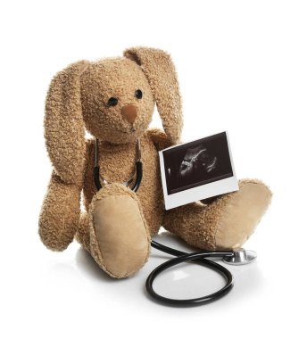 Ultrasound photo of baby and toy rabbit on white background. Concept of pregnancy clipart