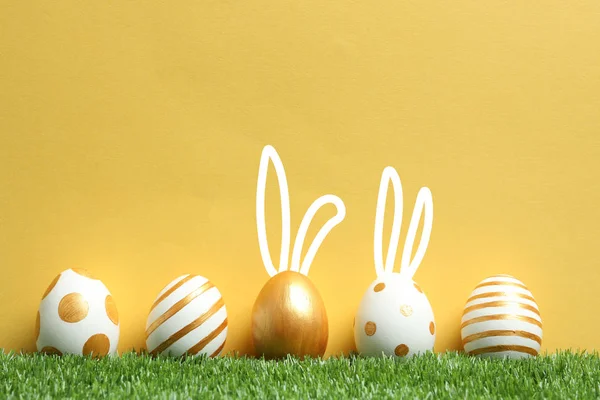 装饰复活节彩蛋和可爱的兔子的耳朵在绿色草地上反对颜色的背景 文本的空间 — 图库照片