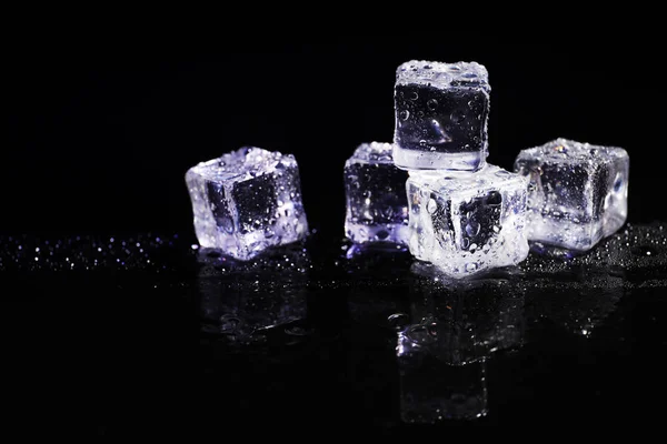 Pile of crystal clear ice cubes on black background