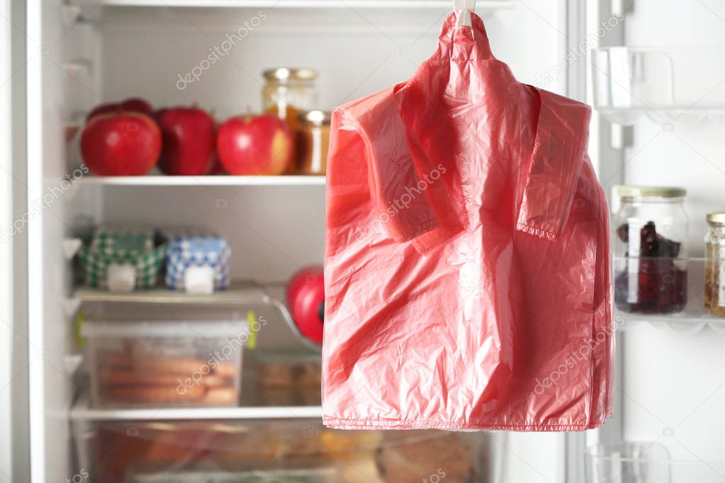 Many plastic bags near refrigerator with products. Space for text