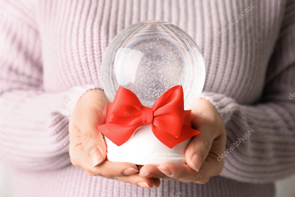 Woman holding empty snow globe with red bow, closeup