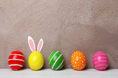 Paskalya yumurtaları ve sevimli tavşan'ın kulakları renk arka plan karşı masada dekore edilmiştir. Metin için yer 