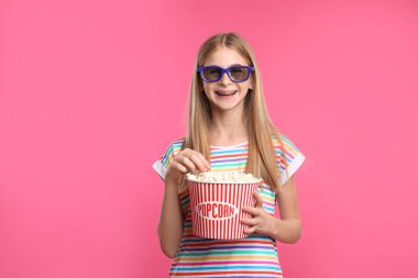 Genç kız ile 3d gözlük ve patlamış mısır sinema sırasında renk arka plan üzerinde göster