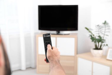 Genç adam ile uzaktan kumanda evde modern TV kanalları arasında geçiş yapma