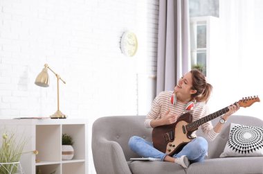 Oturma odasında elektro gitar çalmak kulaklık olan kadın. Metin için yer