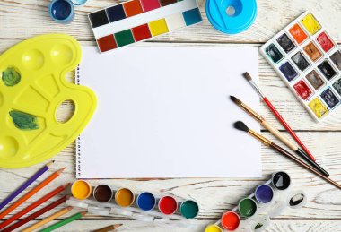 Farklı boyalar, fırçalar ve kağıt ahşap arka plan üzerinde düz yatıyordu kompozisyonu. Metin için yer