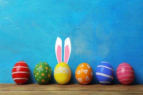 装饰复活节彩蛋和可爱的兔子的耳朵在桌子上的颜色背景 文本的空间 — 图库照片