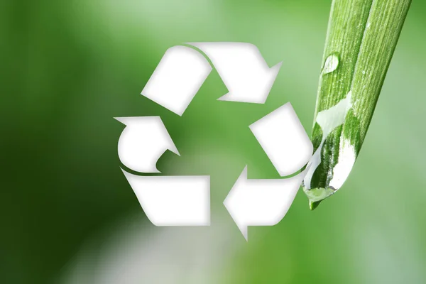 Symbol of recycling on blurred green background, closeup