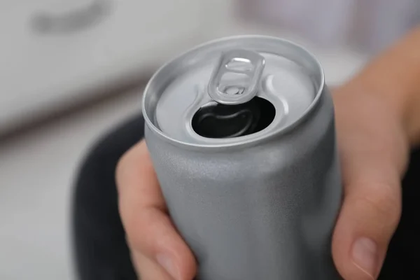 Man holding open aluminum can on blurred background, closeup. Space for design