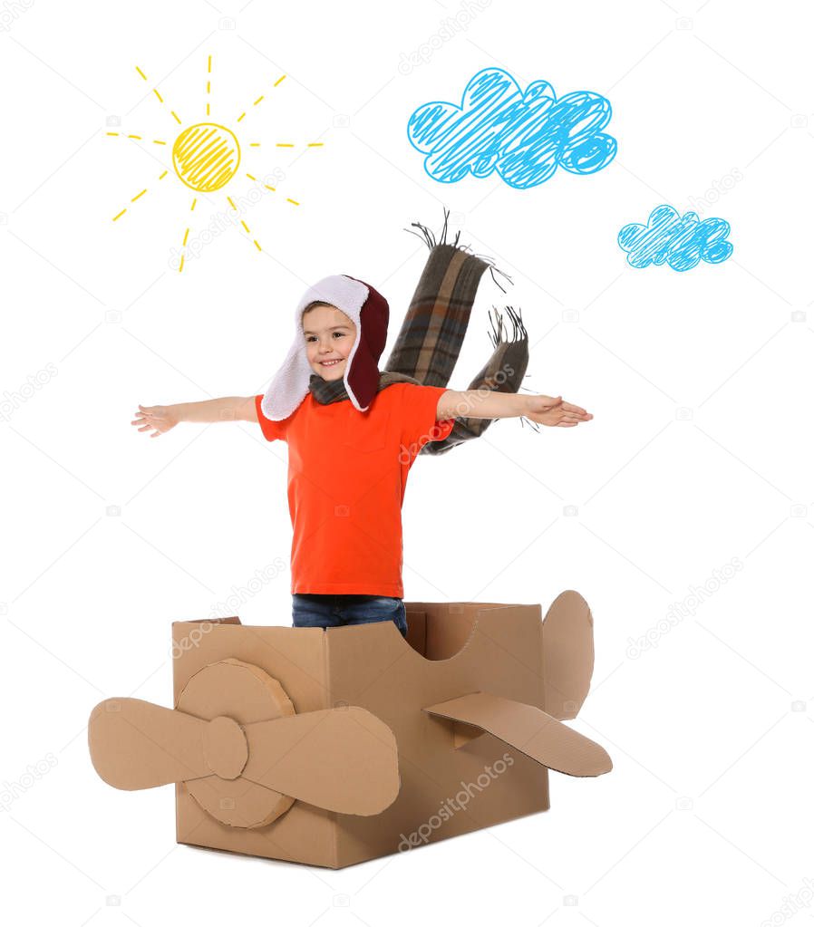 Cute little boy playing with cardboard plane and drawing of clouds on white background