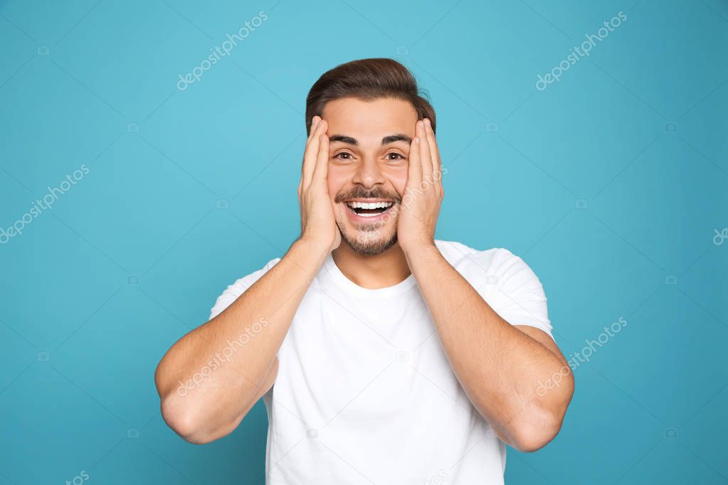Portrait of young man laughing on color background