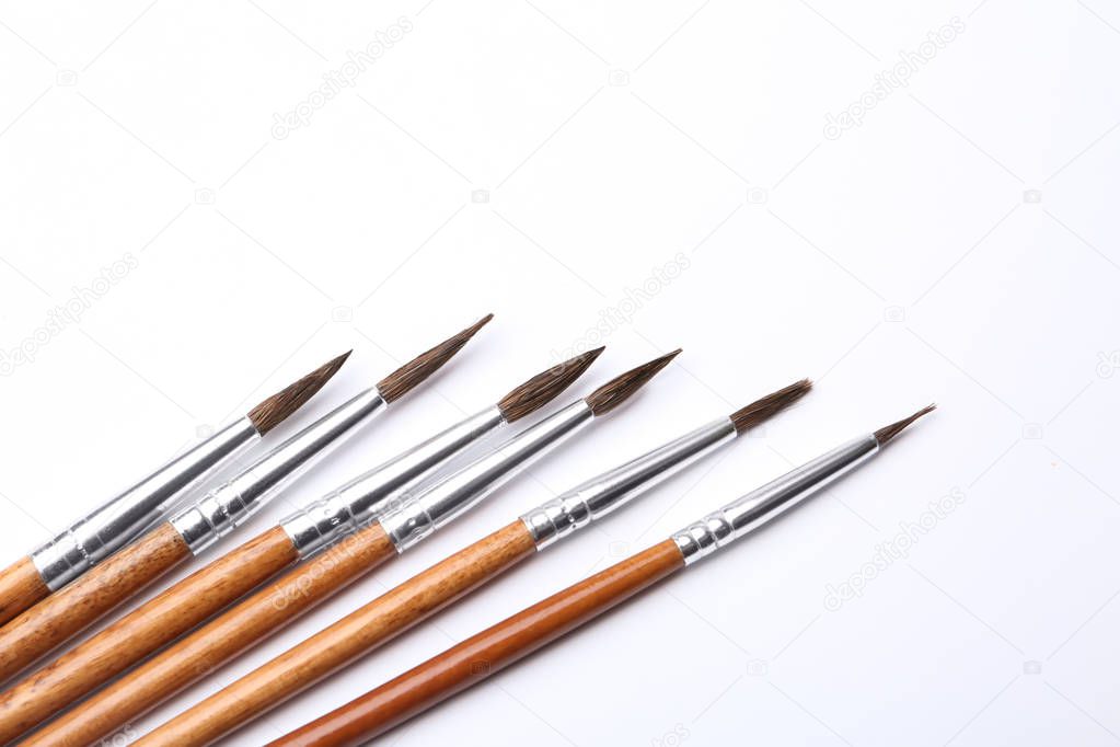 Different paint brushes on white background, top view