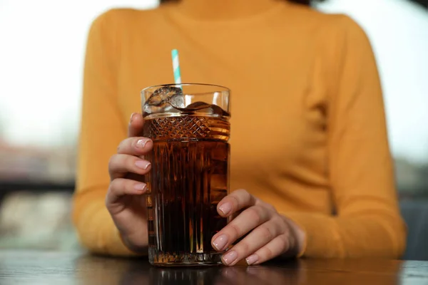 屋内では クローズ アップのテーブルでコーラをさわやかなガラスを持つ女性 — ストック写真